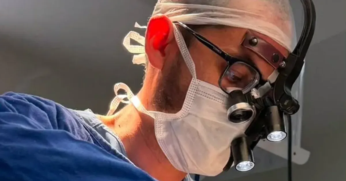 Cirurgião bucomaxilofacial de máscara e lupas de aumento durante uma cirurgia