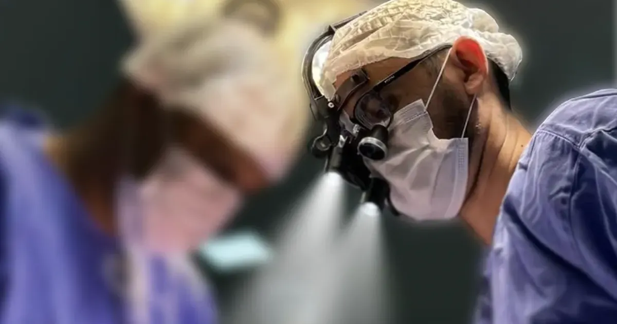 Cirurgião com lupas iluminadas durante uma cirurgia oral